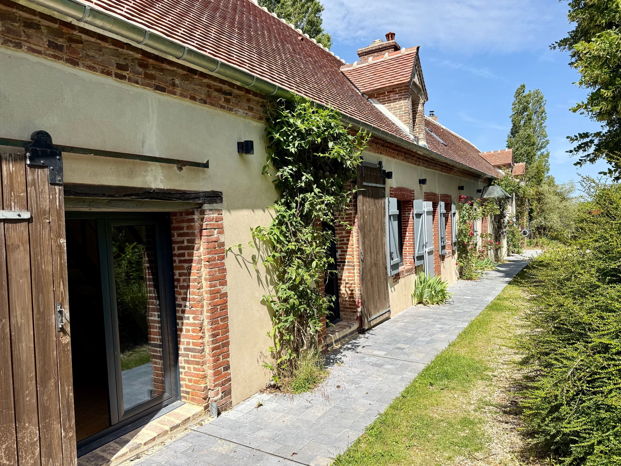 Le long de la façade sud, les portes de grange coulissantes et le chemin dallé