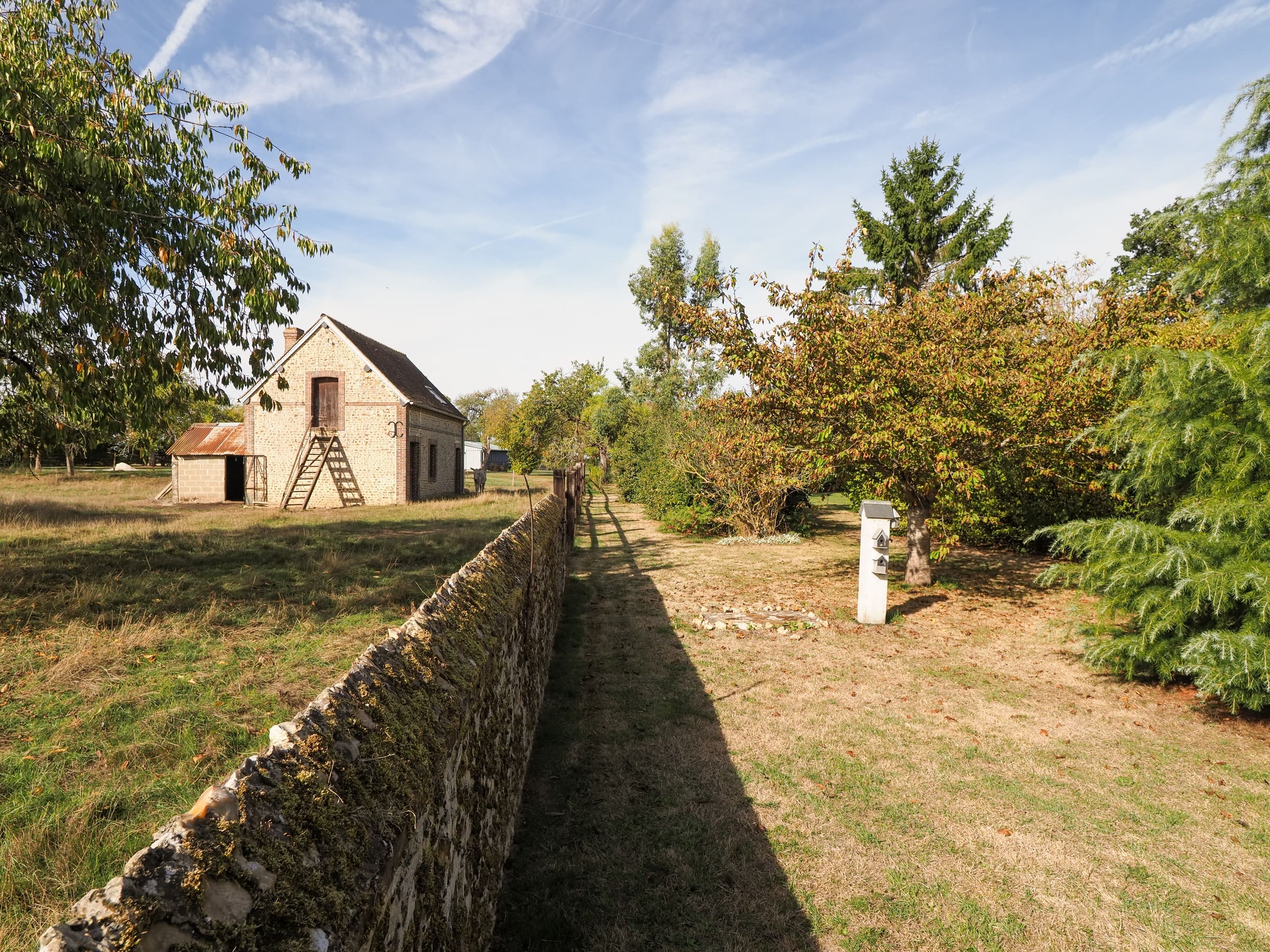 Un vieux mur de pierre, le verger et une petite dépendance en brique