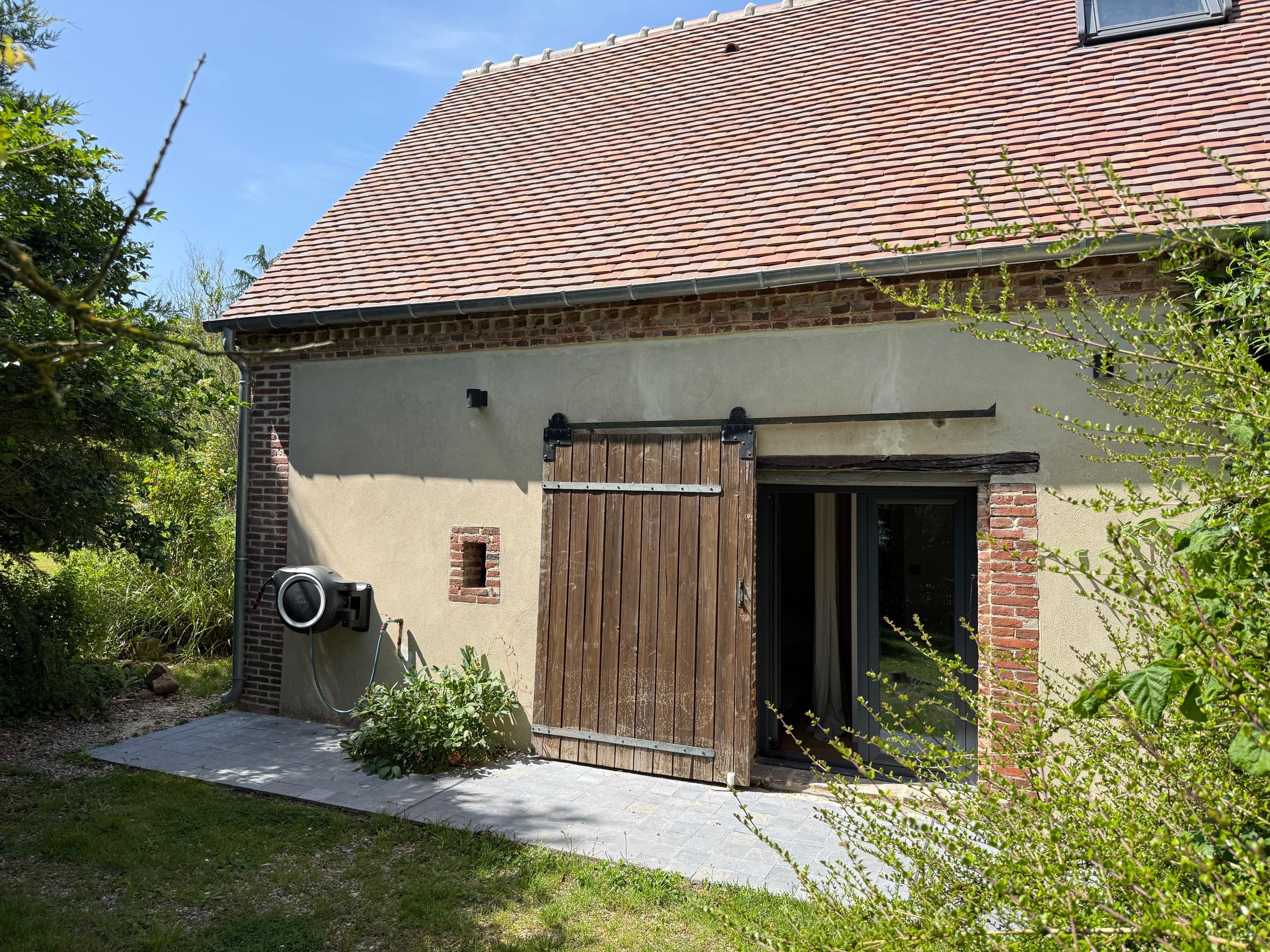 Le pignon et sa porte de grange coulissante devant une baie vitrée