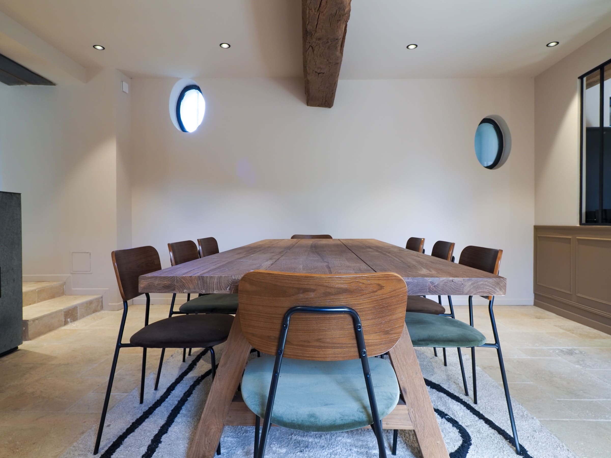 La salle à manger, sa grande table en bois et ses fenêtres rondes
