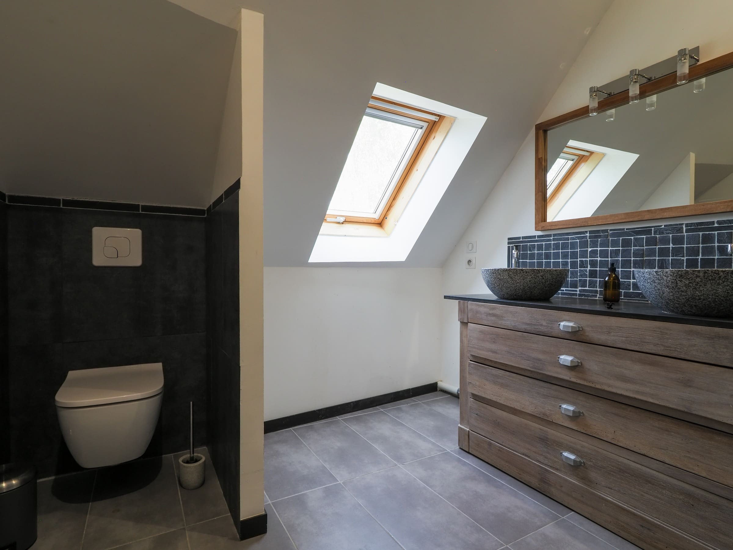La grande salle de bains de la Junior Suite : double vasque, toilettes et fenêtre de toit