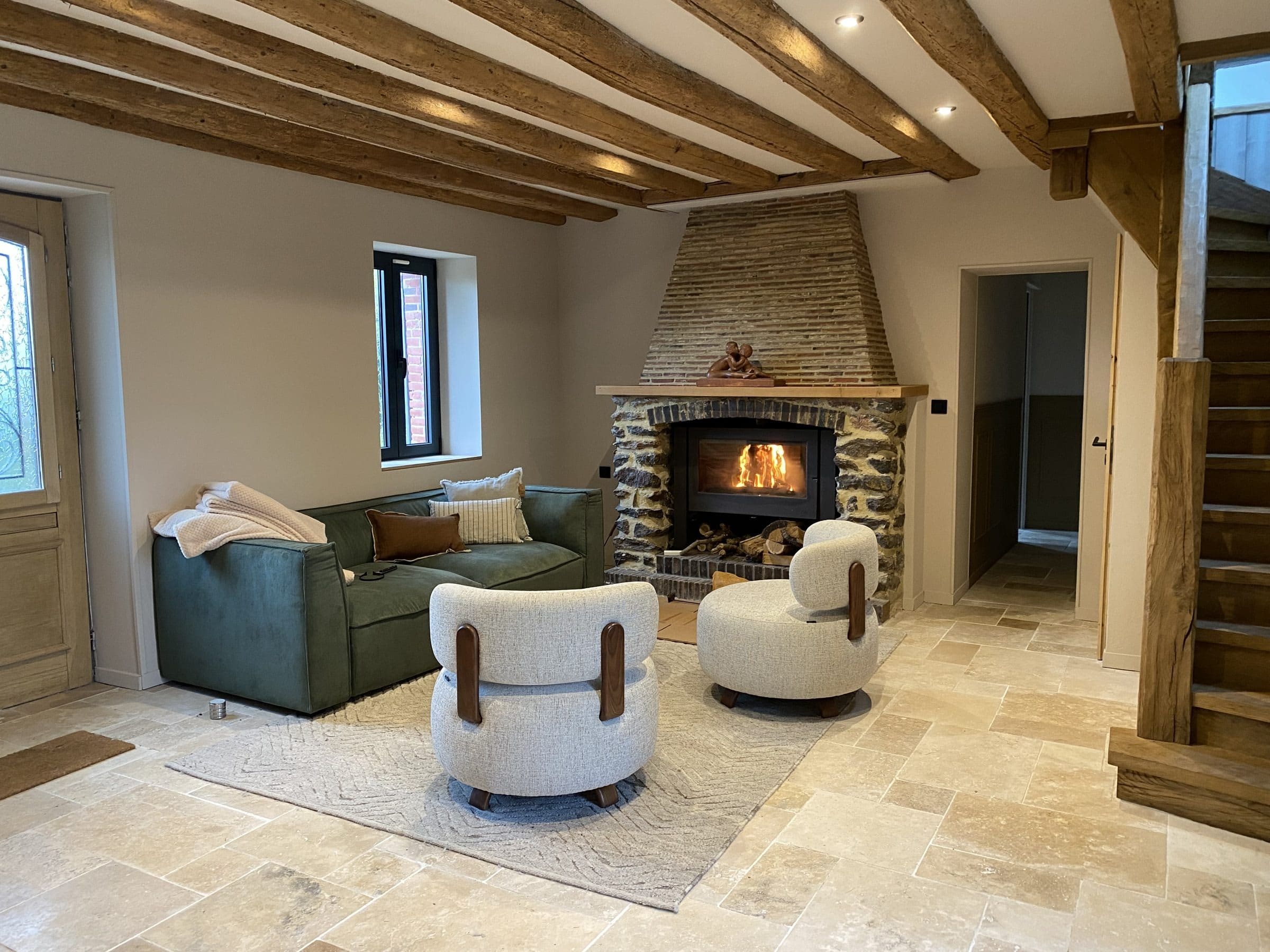 Le salon, ses poutres et un feu dans la cheminée