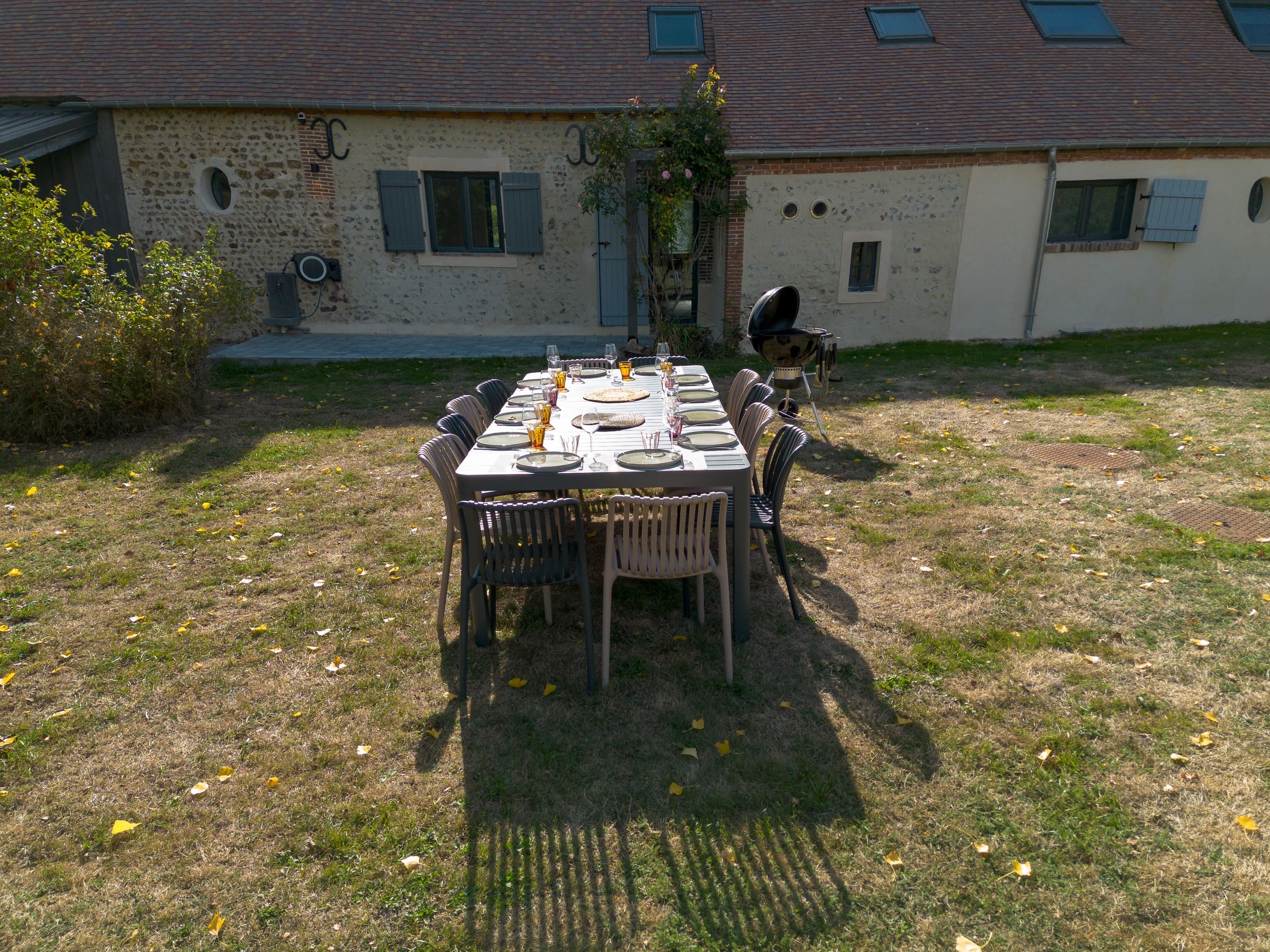 Une table de douze dressée sur la pelouse devant la façade nord, le barbecue à côté