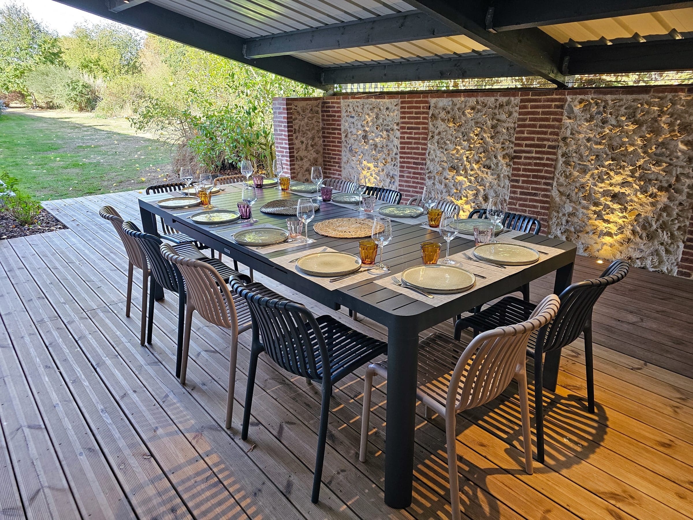 La table dressée sous la terrasse couverte, ouverte sur le jardin